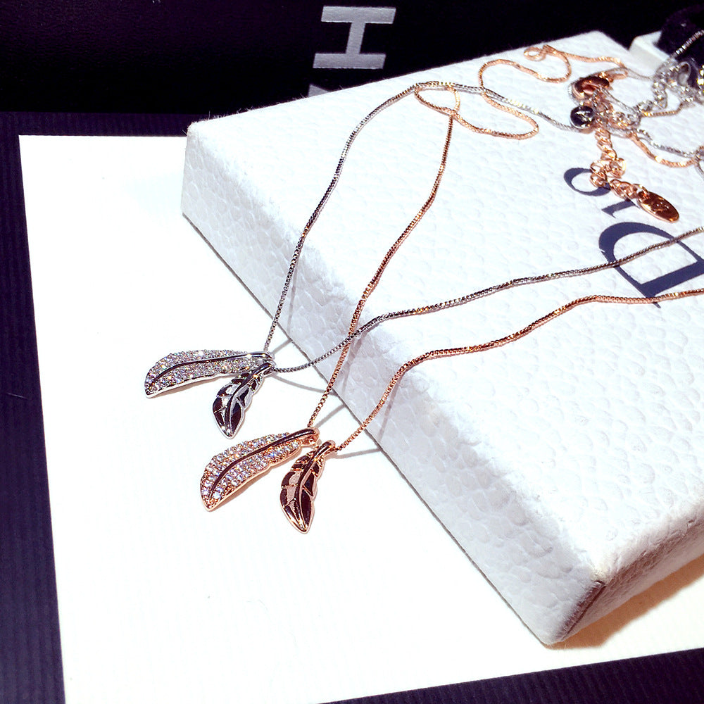 Rose gold necklace with leaf pendants on a white box